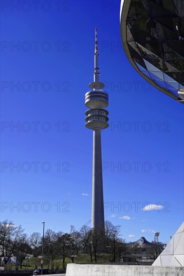 The Olympic Tower in Munich is reflected in the facade of a modern building, BMW WELT, Munich,