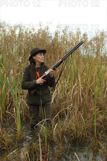 Huntress standing in the water, waiting eagerly for approaching ducks on the occasion of a water
