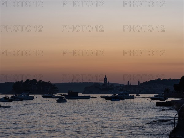 Boats anchoring in a bay, church towers, evening mood after sunset over Rab, town of Rab, island of