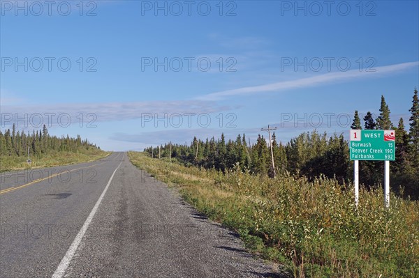 Road leads as endless grades through wilderness, no traffic and one traffic sign, Alaska Highway,