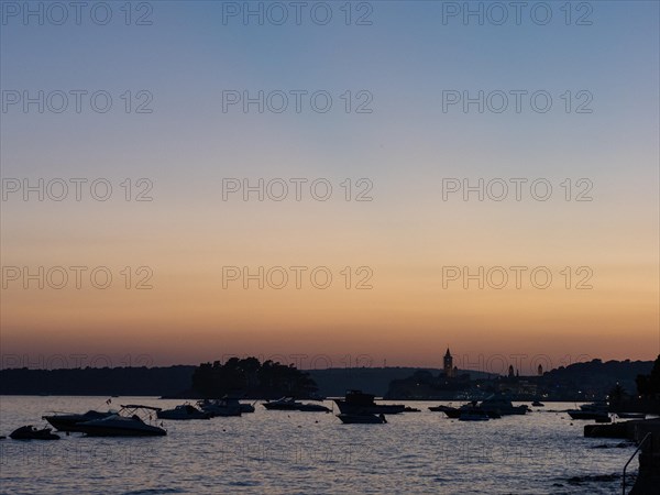 Boats anchoring in a bay, church towers, evening mood after sunset over Rab, town of Rab, island of