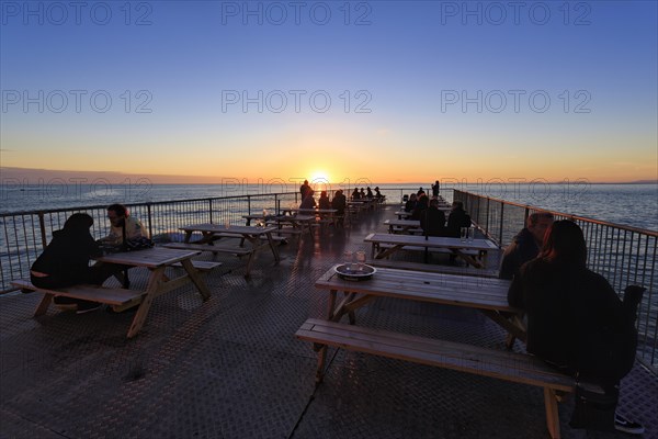 Tourists enjoying sunset on pleasure pier, Royal Pier, Cardigan Bay, Aberystwyth, Ceredigion,