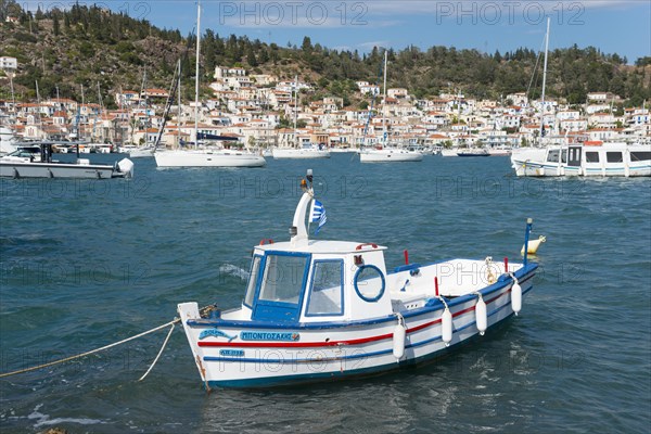 A moored boat in a quiet harbour with a view of sailing boats and white coastal houses, view from