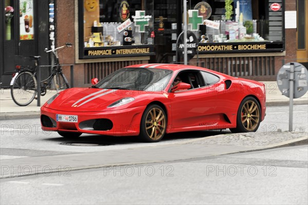 A red Ferrari sports car driving on a city street, Hamburg, Hanseatic City of Hamburg, Germany,