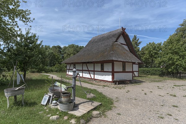 Thatched half-timbered barn, in front a water pump with washing tubs from the 19th century,