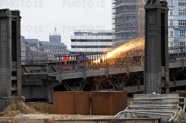 Worker on construction site during welding work with sparks flying in the twilight, Hamburg,