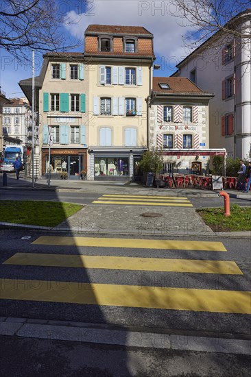 Old pastel-coloured houses with white windows and wooden shutters and the Cafe Vieil Ouchy on a