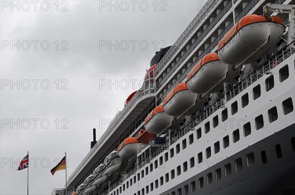 Side view of a cruise ship Queen Mary 2, with lined up lifeboats and flags, Hamburg, Hanseatic City