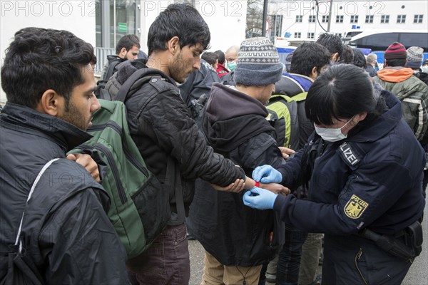 After arriving at Rosenheim station, refugees are given wristbands by federal police officers for