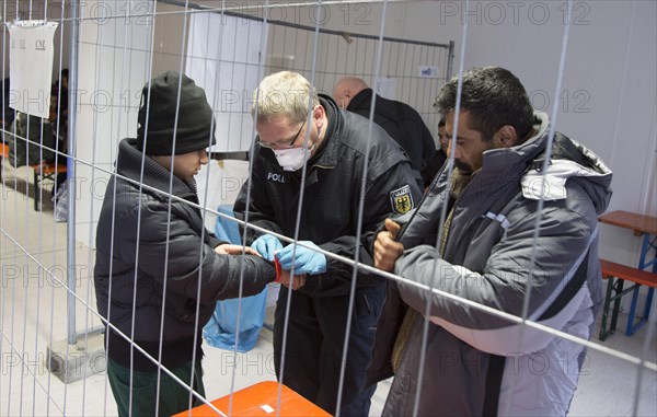 Refugees are searched by federal police officers after their arrival at Rosenheim station,