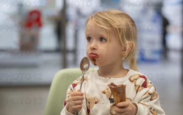 Interior shot, girl, 2-3 years, blonde, eating chocolate ice cream, ice cream, waffle, spoon, mouth
