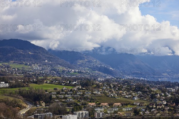 View of the outskirts of Vevey and mighty white spring clouds moving over mountains near Jongny,