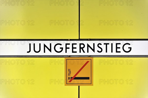 Sign of the underground station 'Jungfernstieg' with no smoking sign on yellow background, Hamburg,