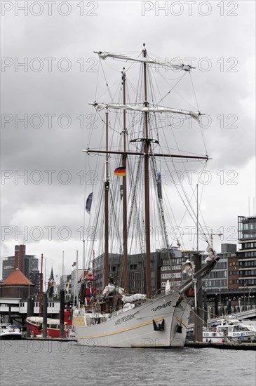 MARE FRISIUM, A large sailing ship in the harbour under a cloudy sky against a backdrop of