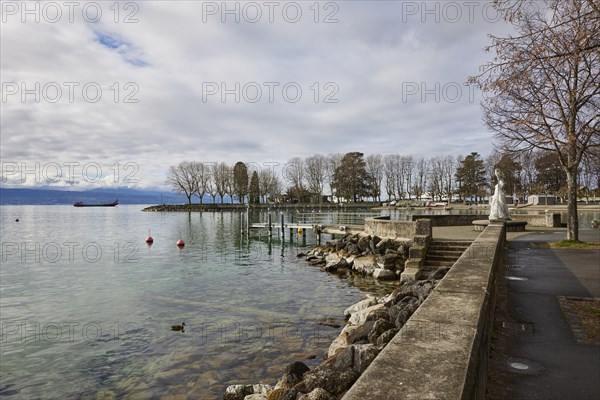 View of Lake Geneva with cargo ship from the lakeside promenade with the statue of the Virgin of