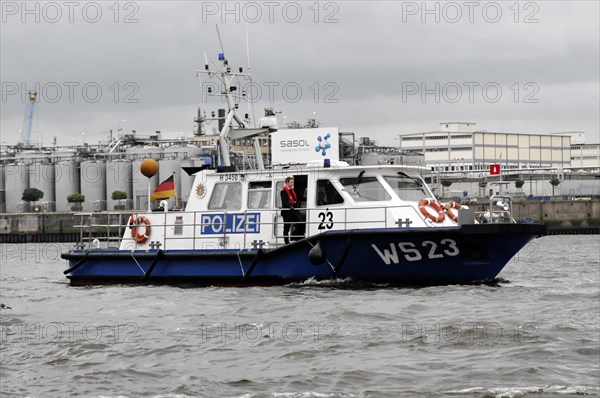 Police boat on the water with crew and cloudy sky in the background, Hamburg, Hanseatic City of