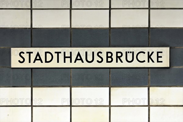 A sign with the inscription Stadthausbruecke on a wall with blue tiles, Hamburg, Hanseatic City of