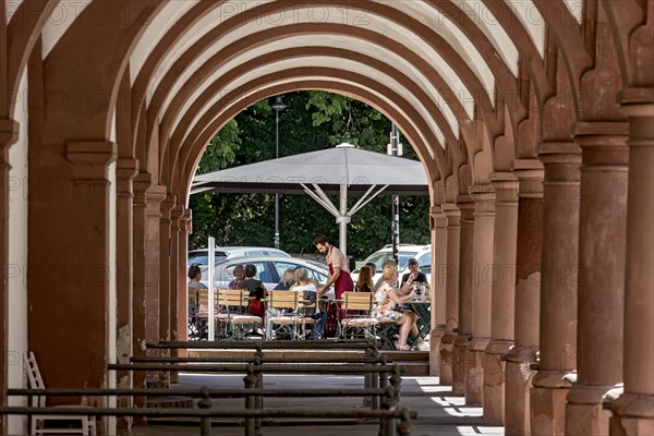 Restaurant and street cafe with waiter and guests, historic market arbours, archway with columns,