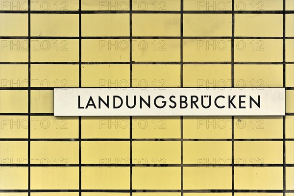 A sign with the inscription 'Landungsbruecken' on a yellow tiled wall, Hamburg, Hanseatic City of