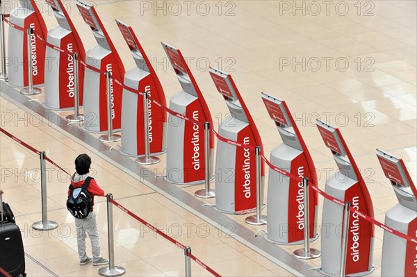 A child standing in front of self-service check-in machines in an airport queue, Hamburg, Hanseatic