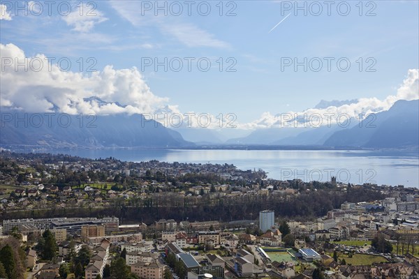 View of Vevey and Lake Geneva with cloudy, misty mountains in the background from Jongny,
