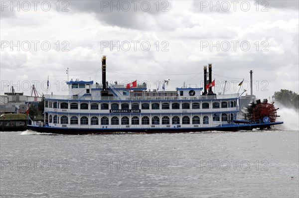 An antique paddle steamer named 'Louisiana Star' sailing on the water against a cloudy sky,