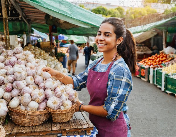 Food, spices, garlic, Allium sativum, many bulbs on a market stall, woman as saleswoman in Italy,