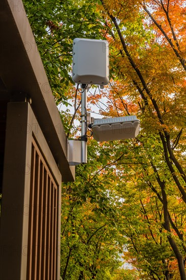Wifi communication equipment mounted on top of wooden gazebo under trees in public park in South