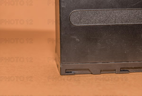 Closeup side view of used Lithium-ion battery on brown background. Selective focus on locking