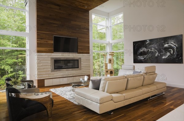 Living room with creamy beige colored L-shaped leather sofa and gas fireplace inside luxurious