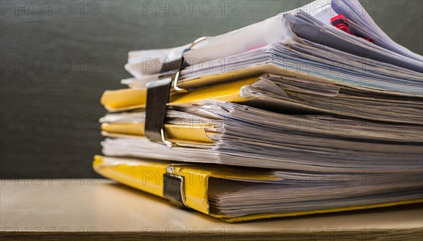 Folders with yellow tabs are piled up untidily on a table, symbolising bureaucracy, AI generated,