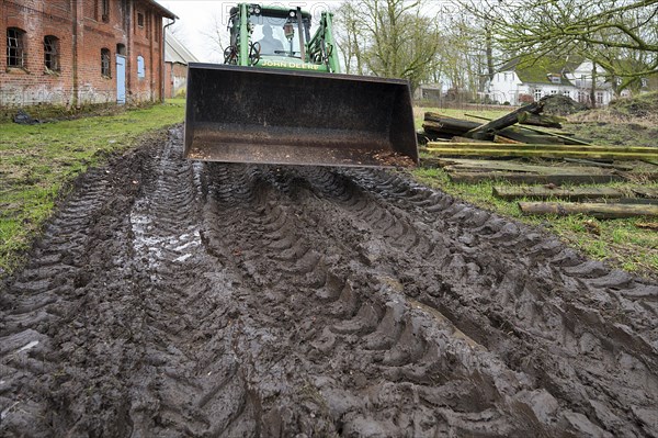 Tractor with tyre tracks on soaked ground on a farm, Othenstorf, Mecklenburg-Vorpommern, Germany,