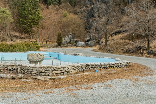 Empty water fountain with large concrete ornamental center piece in mountainside public park in