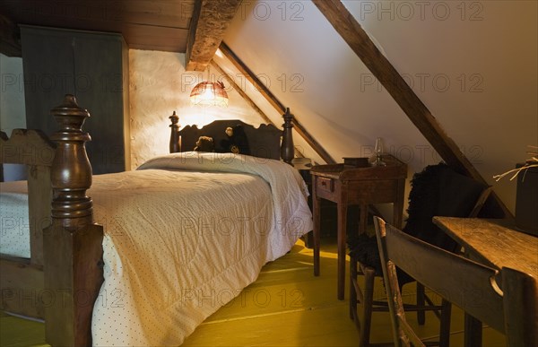 Antique wooden four-poster single bed and armoire in bedroom on upstairs floor inside old 1785