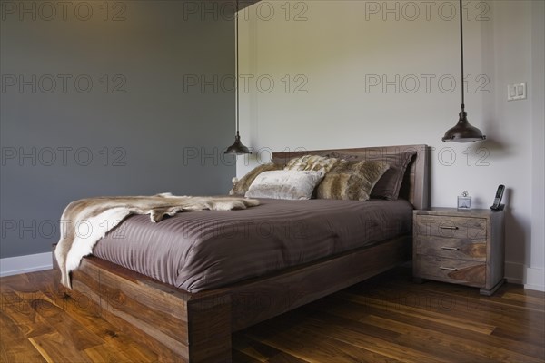Queen size wooden base bed covered with fur pelt throw in guest bedroom inside luxurious home,
