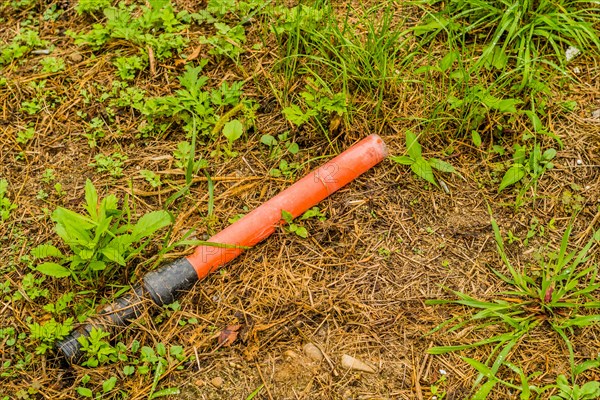 An orange tube on the grassy ground, symbolizing the issue of littering in natural areas, in South