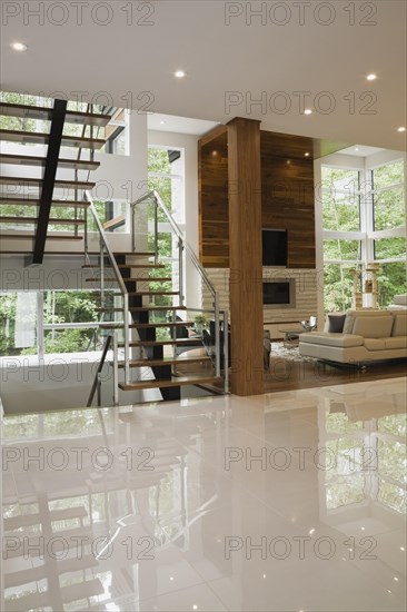 Wood, metal and glass staircase leading to living room with creamy beige L-shaped leather sofa