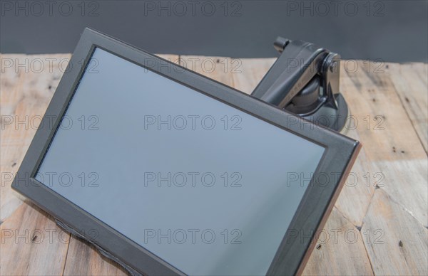 Front view of automobile navigation with attached mounting arm on wooden table with black