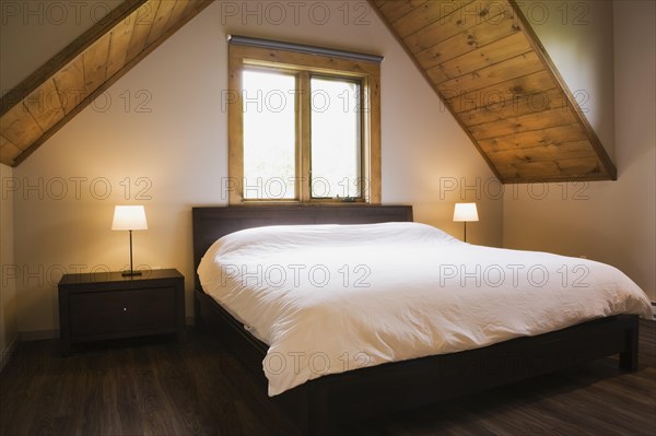 King size bed in master bedroom on upstairs floor inside contemporary style log home, Quebec,