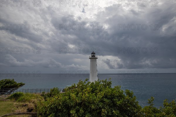 Le Phare du Vieux-Fort, white lighthouse on a cliff. Dramatic clouds with a view of the sea. Pure
