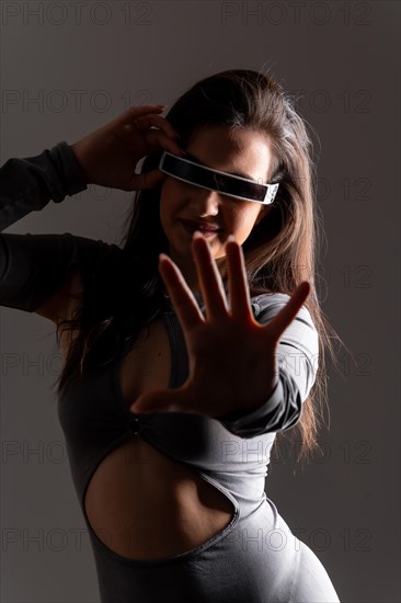 Studio portrait with grey background of a futuristic woman playing and gesturing using virtual