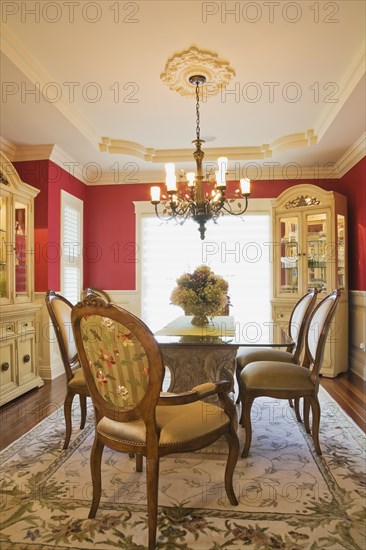 Glass top table with high-back wooden and upholstered chairs in dining room with buffets inside