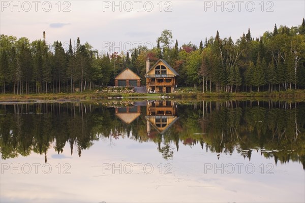 Garage and handcrafted two story spruce log cabin home with fieldstone chimney and green sheet