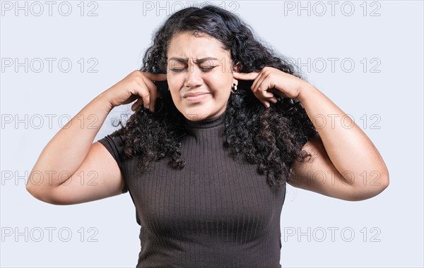 Frustrated young woman covering her ears ignoring something isolated. Displeased girl in glasses