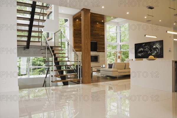 Wood, metal and glass staircase leading to living room with creamy beige L-shaped leather sofa