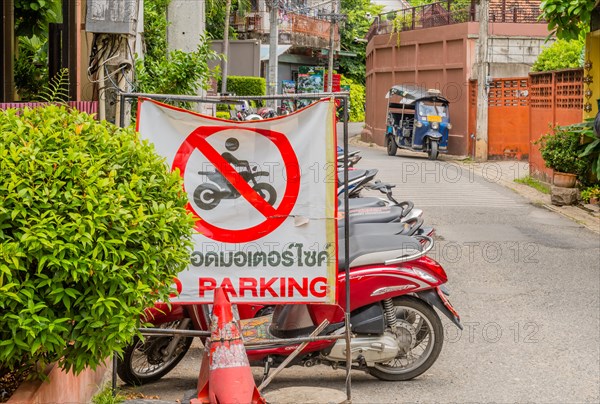 No parking sign displayed on a busy street with motorbikes in the background, in Chiang Mai,
