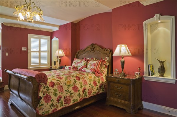 Wooden sleigh bed and night table in master bedroom on upstairs floor inside elegant style home,