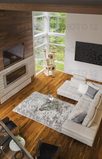 High angle view of living room with creamy beige colored L-shaped leather sofa and gas fireplace