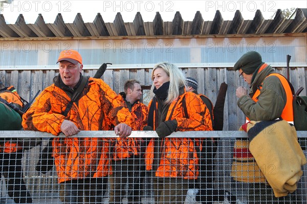 Wild boar (Sus scrofa) start of hunt, hunter and huntress in high-visibility waistcoats on trailer,