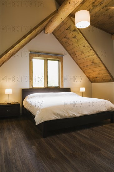 King size bed in master bedroom on upstairs floor inside contemporary style log home, Quebec,
